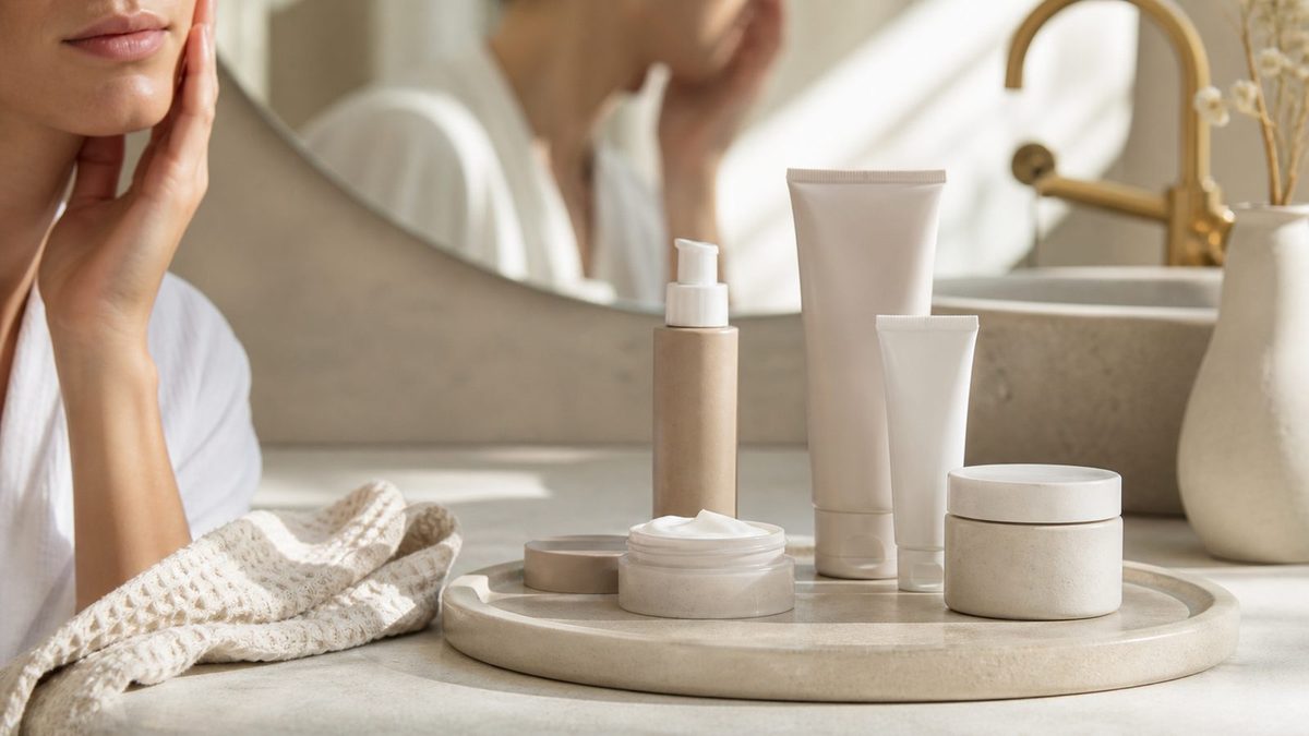 Neutral skincare bottles and jars on a stone bathroom tray