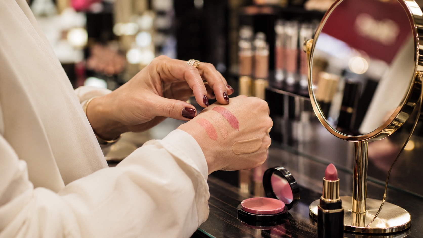Cream blush and makeup brushes on a beauty counter in soft editorial light.