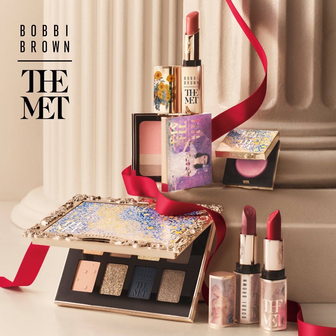 Bobbi Brown x The Met makeup collection arranged among pale columns and a red ribbon.
