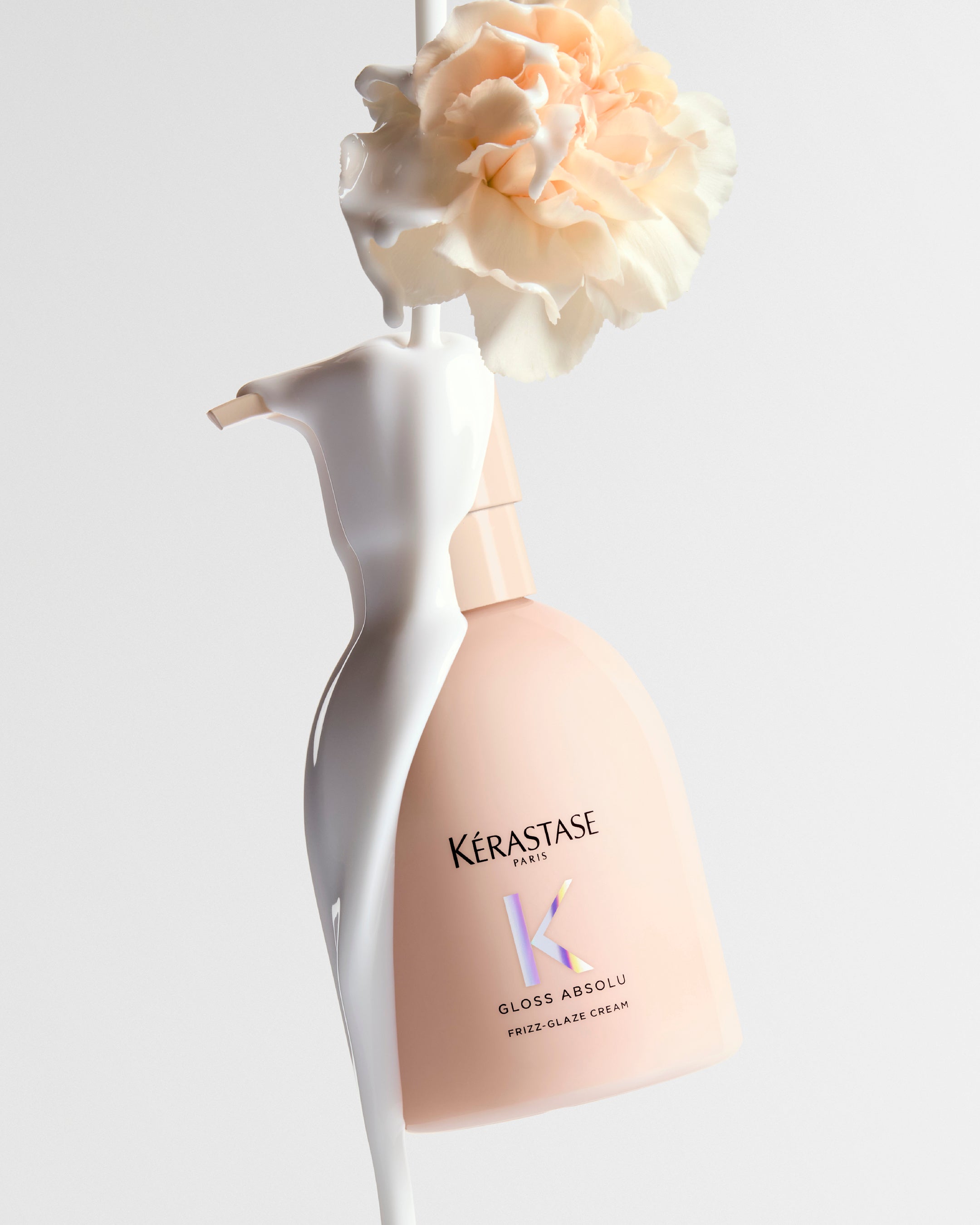 Kérastase Gloss Absolu Frizz-Glaze Cream bottle with cream and a pale flower in the brand’s campaign photograph.