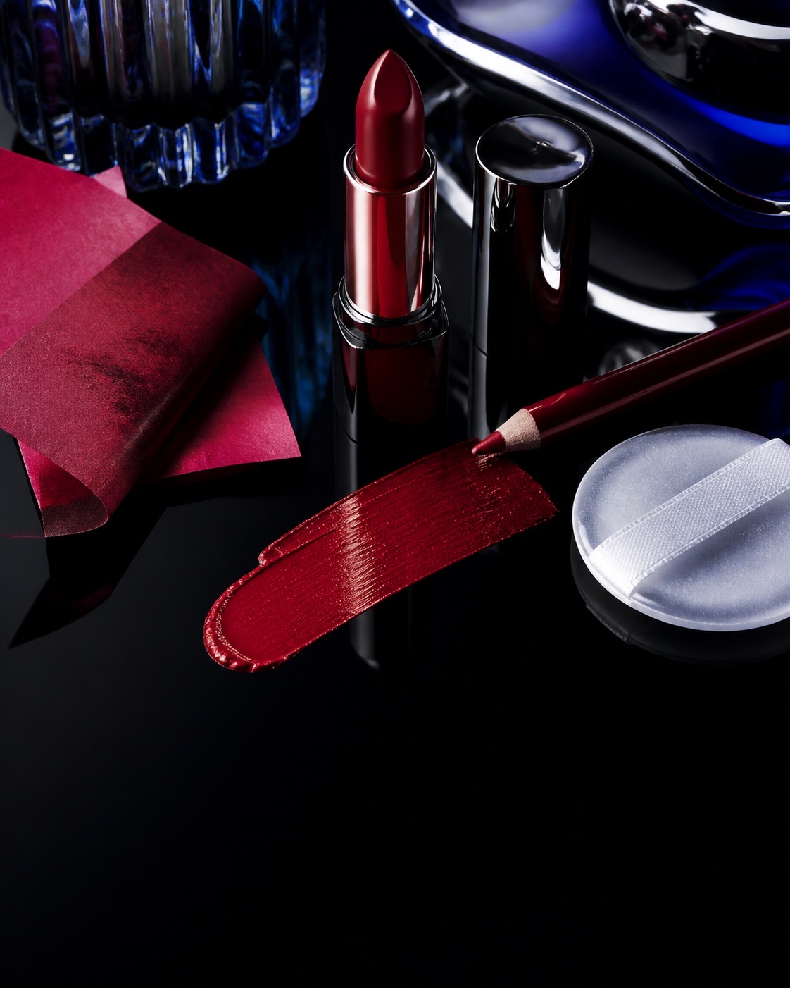 Unbranded red lipstick, lip pencil and a smooth colour swatch in a single editorial still life
