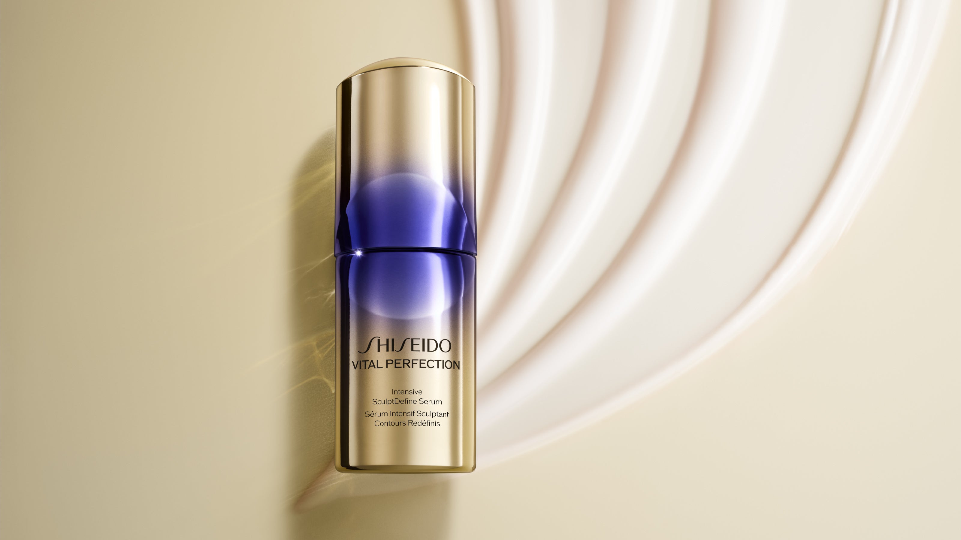 Gold and deep-purple Shiseido Vital Perfection Intensive SculptDefine Serum bottle beside a curved white cream swirl on a pale gold background.